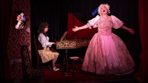 Performer as Marie Antoinette singing with the accompaniment of a keyboard player